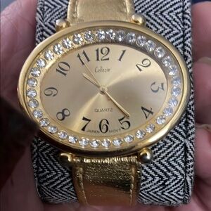 Gold Oval Face Watch with Gemstone Bezel and Metallic Band